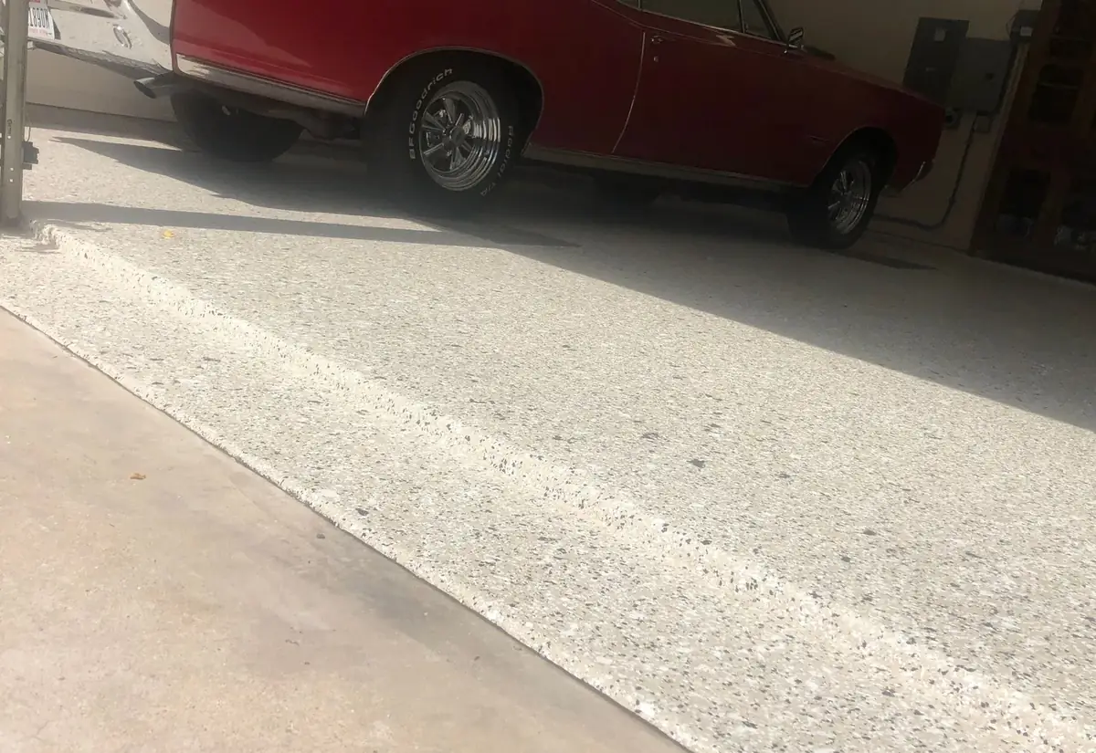A red car is parked in a garage on a concrete floor.