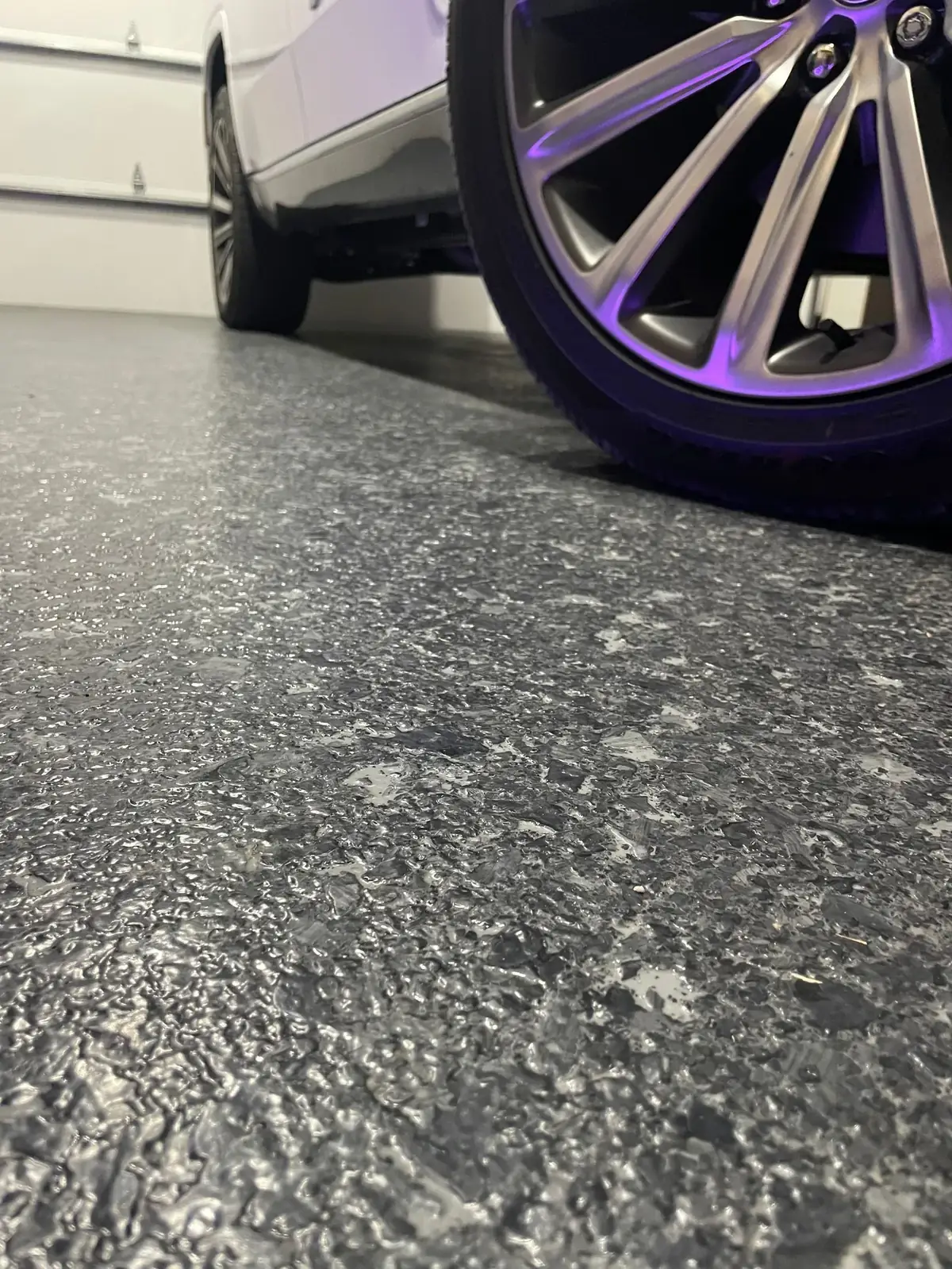 A car is parked in a garage with a purple wheel.