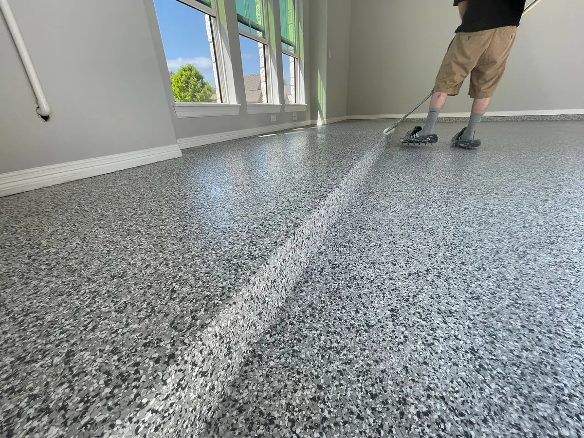 A man is cleaning a garage floor with a mop.