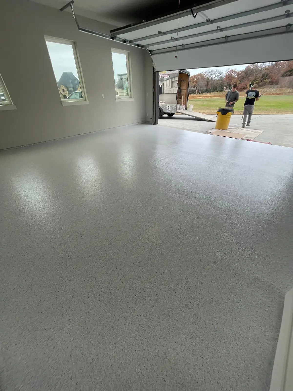 A garage with a concrete floor and a garage door open.
