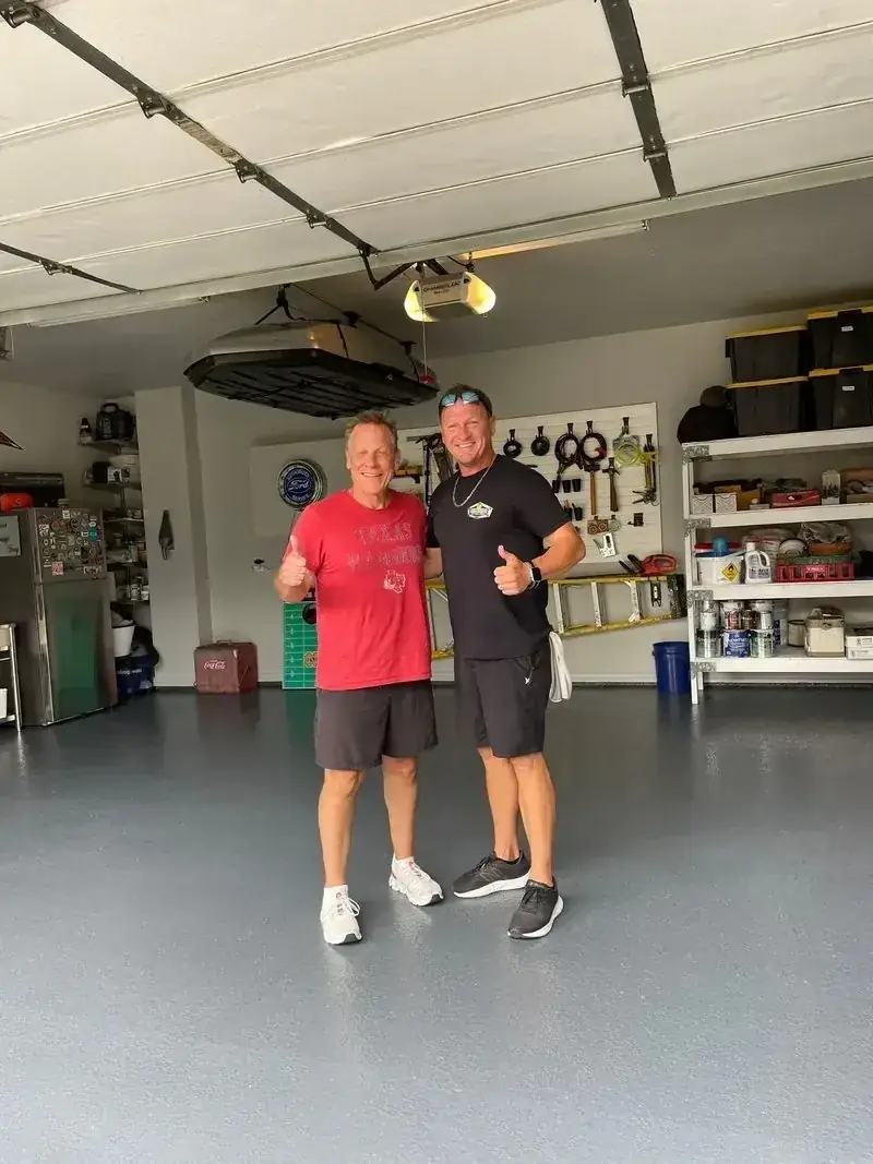 Two men are standing next to each other in a garage.